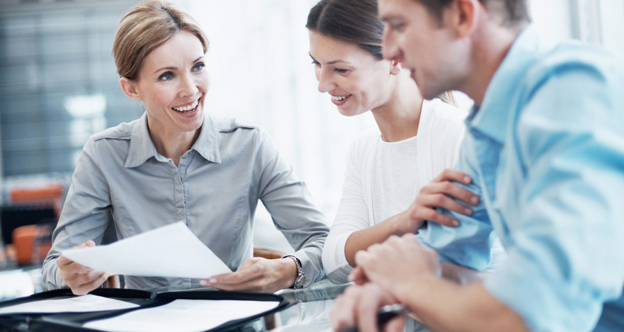 Three people discussing paper work